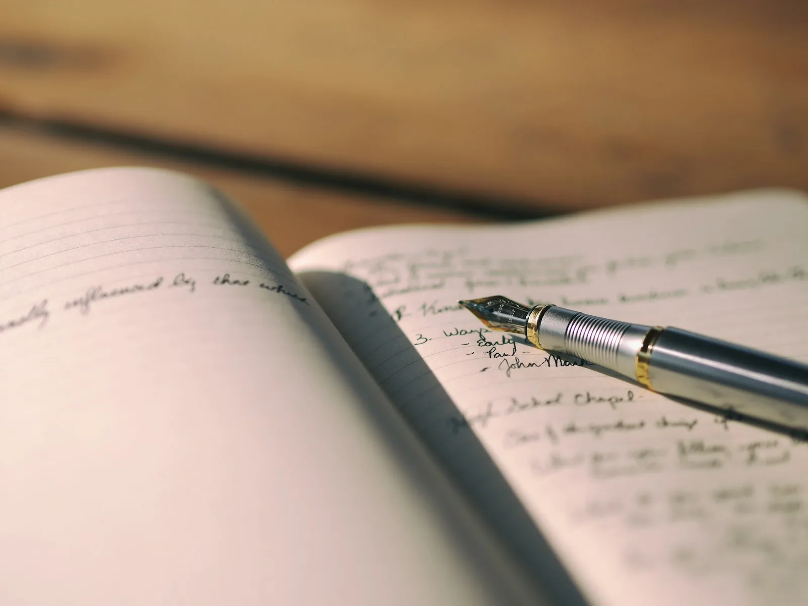 Een opengeslagen schrift met handgeschreven aantekeningen en een vulpen erop.