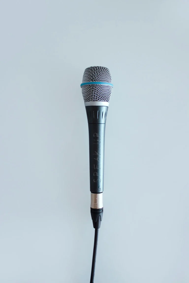 Een handmicrofoon met snoer tegen een egale achtergrond.